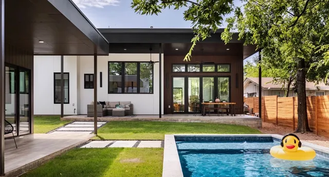 Modern home exterior with a covered patio and pool, seen from the backyard