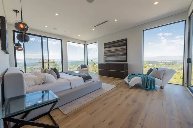Living room with a fireplace, wall-mounted TV, and palm and city views through glass doors