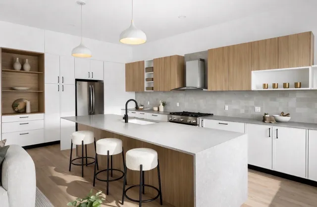 White and oak kitchen with a large island, black pendant lights, and built-in wood shelving