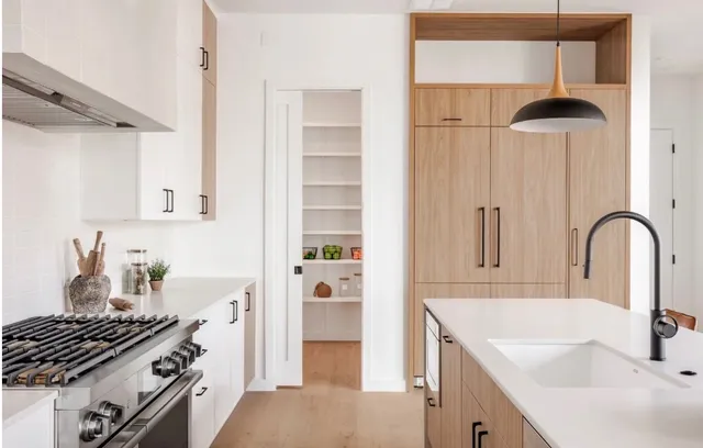 Galley kitchen with walnut cabinetry and a pendant light over the pantry doorway