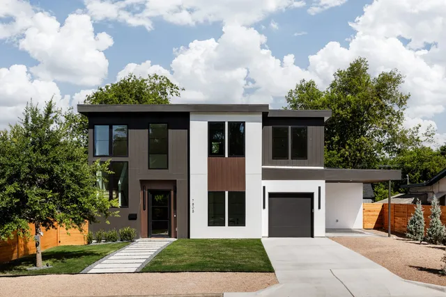 Modern black and white two-story home exterior with a paver walkway