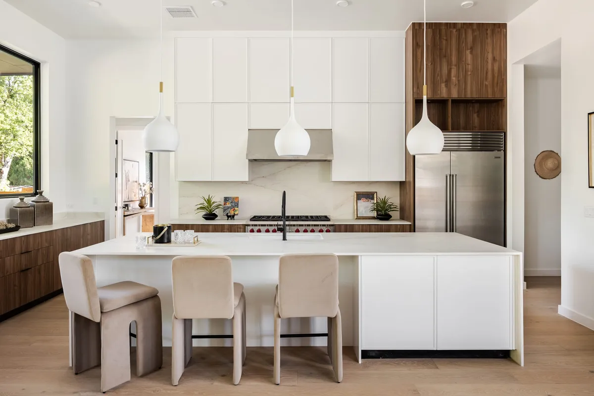 Kitchen with white cabinetry, walnut accents, and pendant lighting