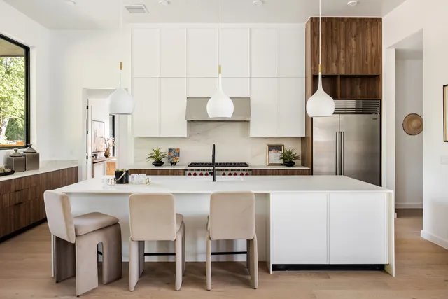 Kitchen with white cabinetry, walnut accents, and pendant lighting