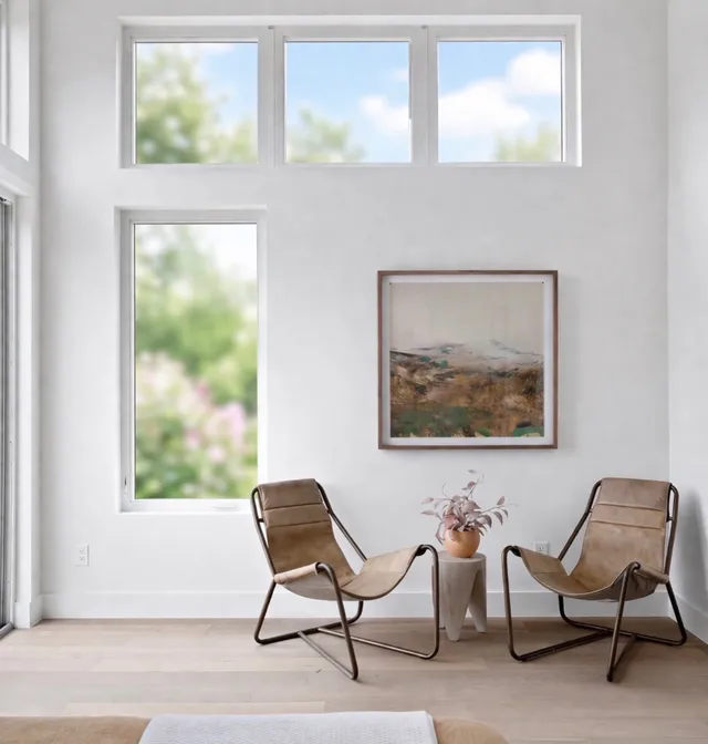 Two leather sling chairs beside tall windows with a framed landscape print
